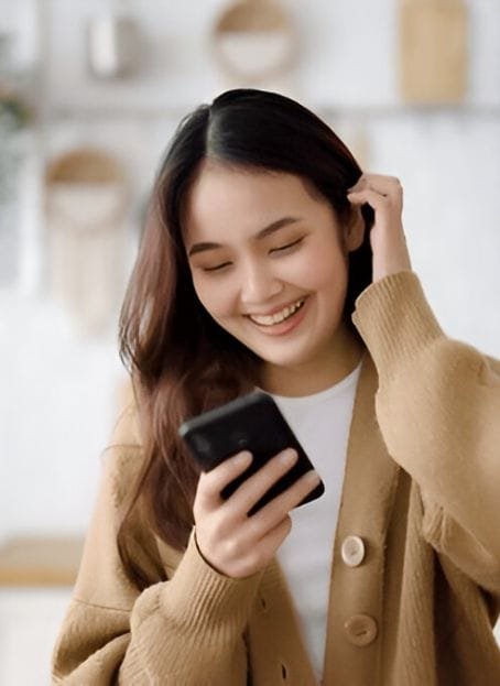 A happy NetWorth+ user smiling while checking their finances on a mobile app, feeling confident and in control of their financial decisions.